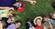 Dzieci kolorowo ubrane leżą w kręgu na trawie