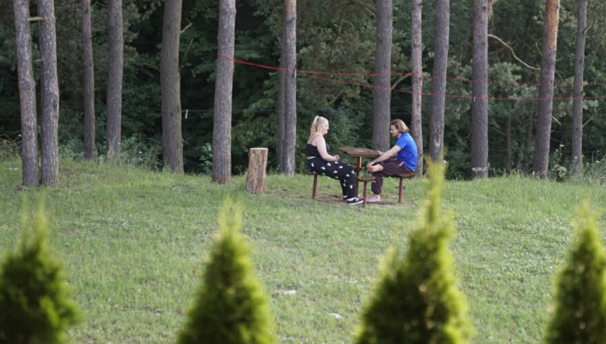 Dwoje młodych ludzi siedzi wśród leśnych drzew przy stoliku